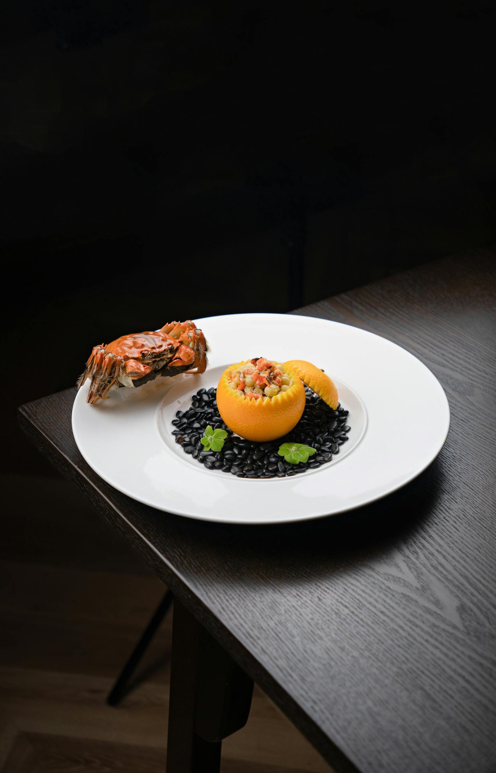 A gourmet seafood presentation featuring a lobster served with black beans and garnish.
