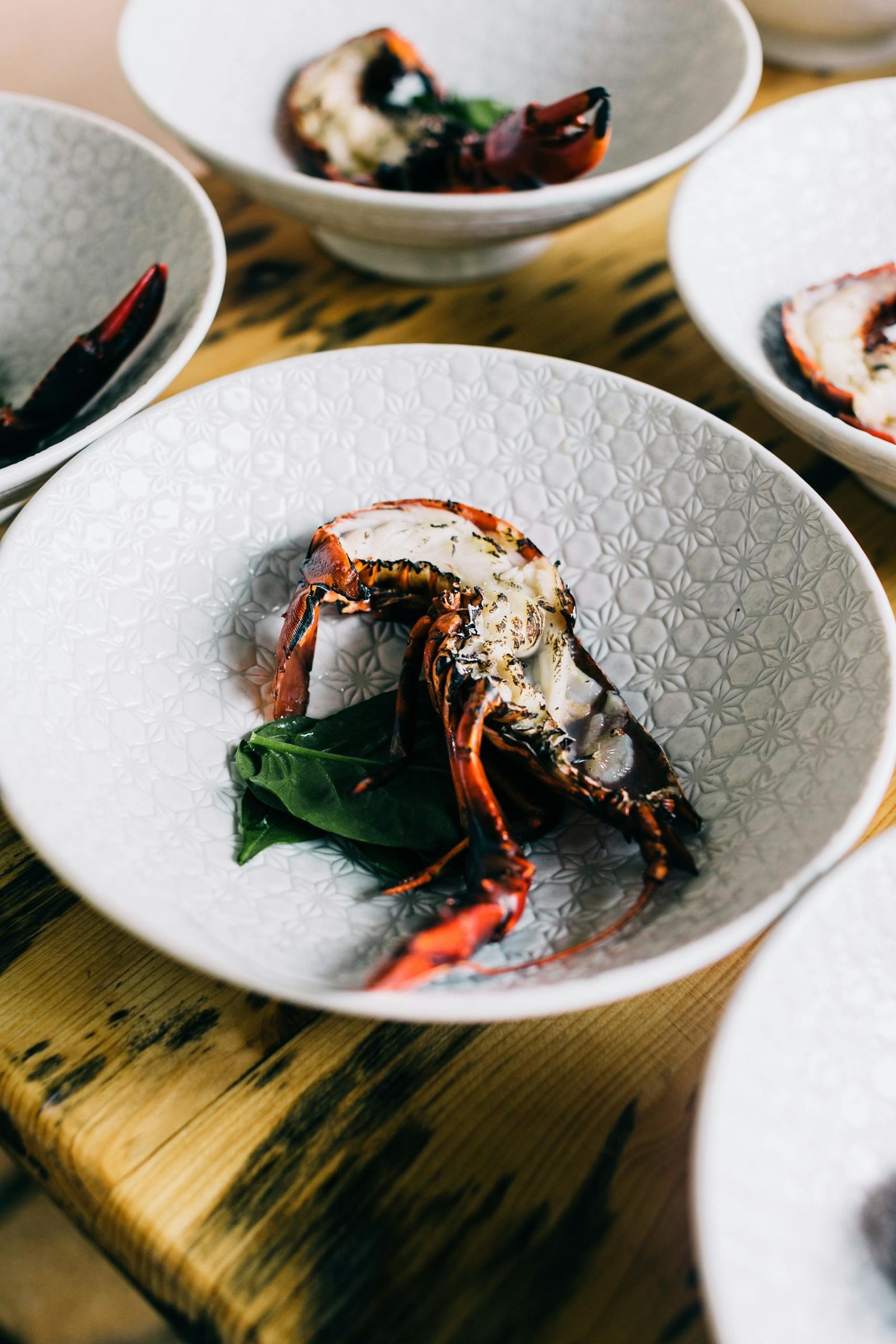From above of fresh appetizing lobster served on white plates on wooden table in modern restaurant with tasty gourmet seafood