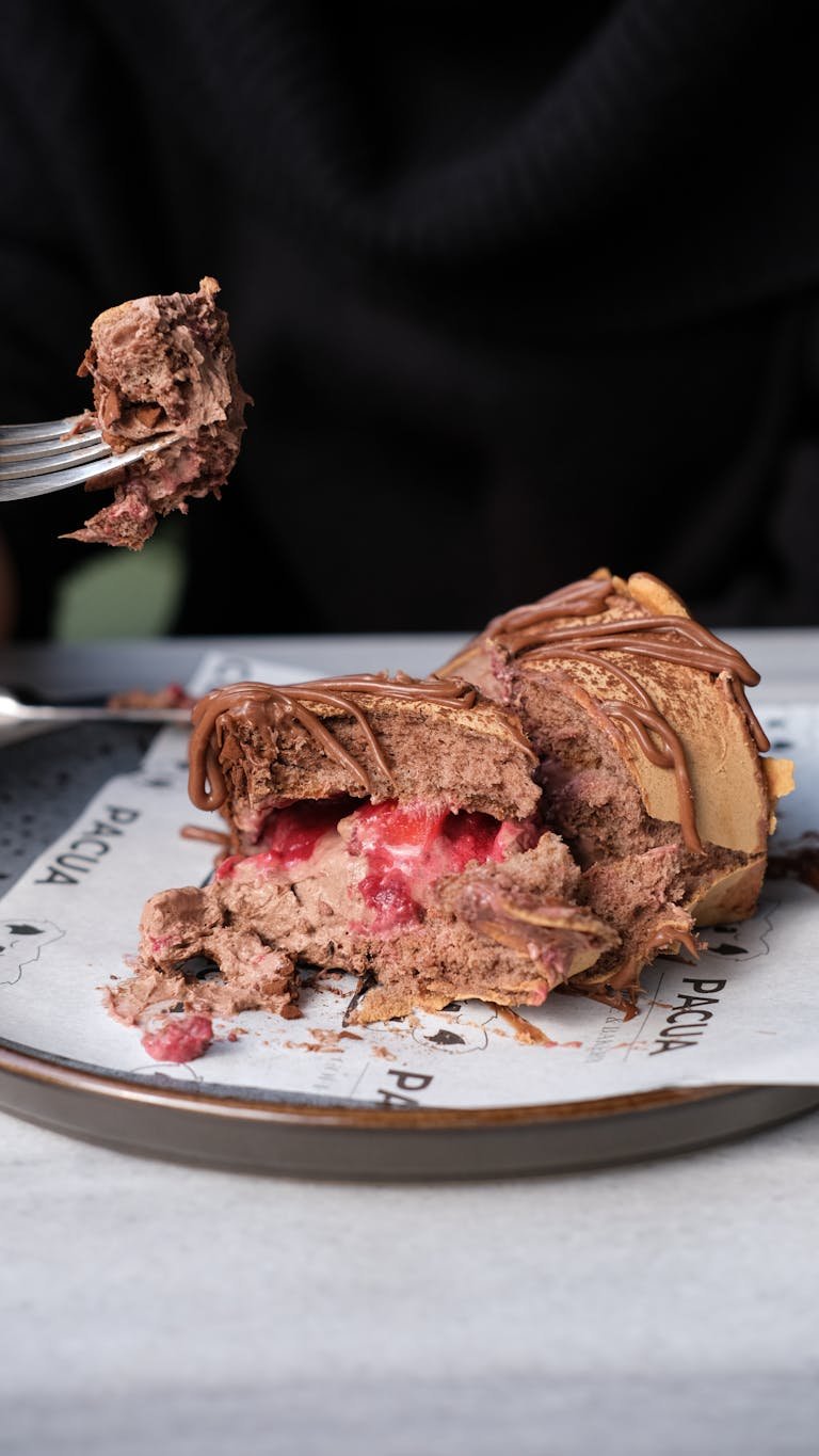 Rich chocolate cake slice with berry filling on a plate, enticing and indulgent dessert.