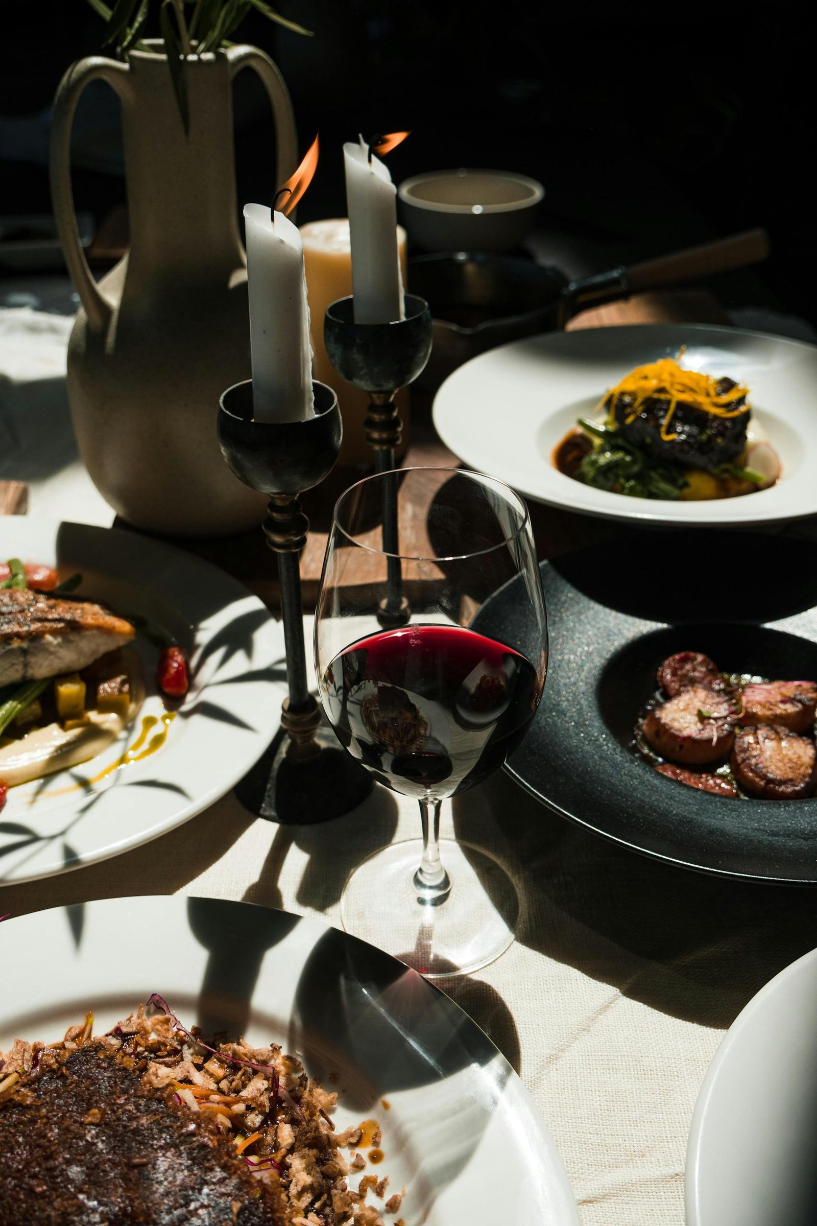 Sophisticated dining setup with gourmet dishes, red wine, and ambiance lighting.